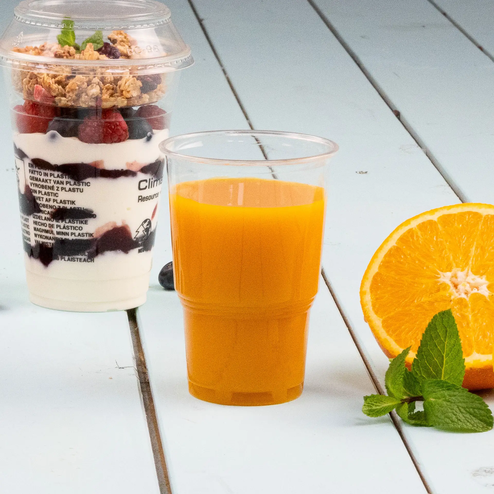 Jeden przezroczysty biodegradowalny PLACup, 250 ml, zaprojektowany do zimnych napojów; częściowo pokazany poniżej innych podobnych kubków.