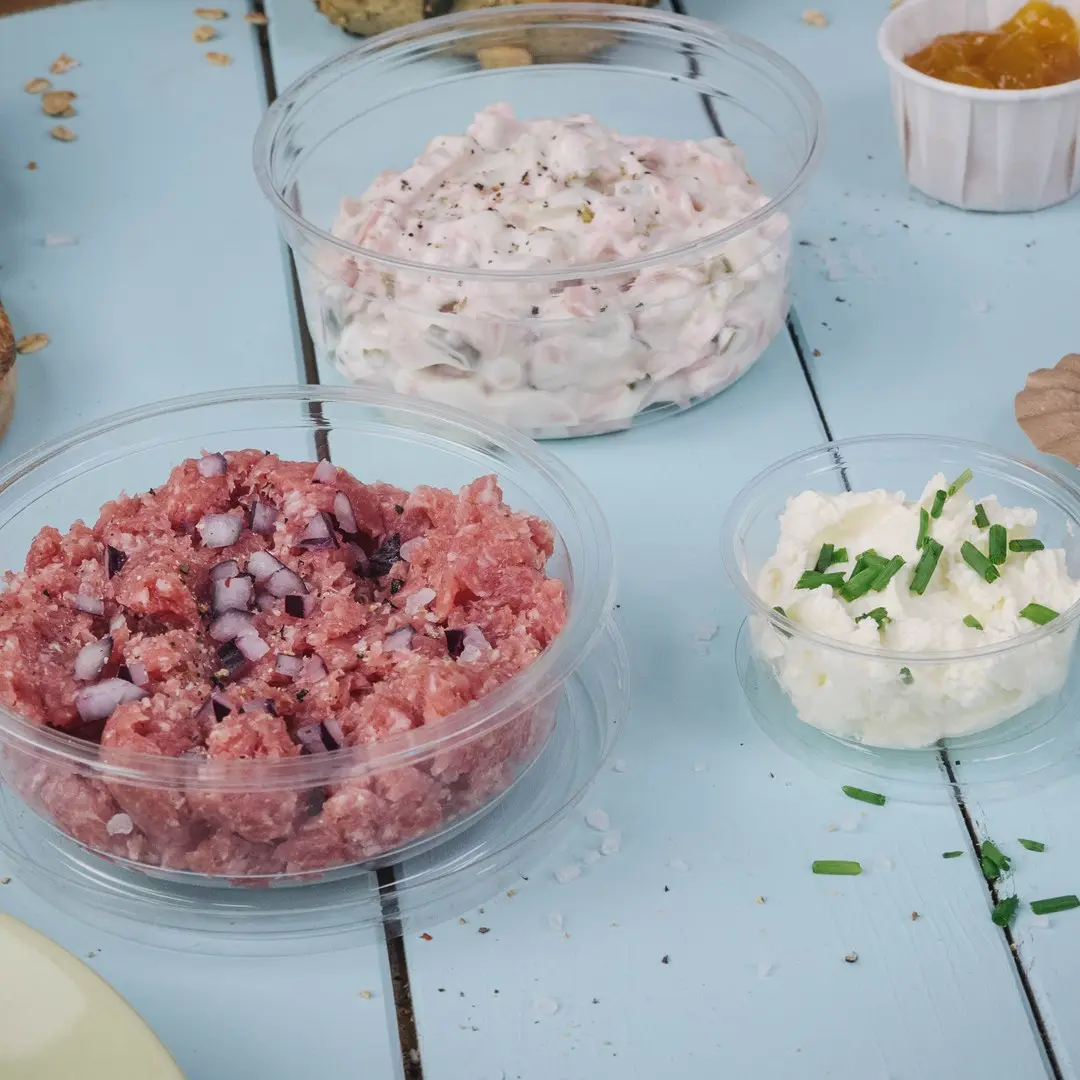 Trzy przezroczyste pojemniki z różnymi pastami: różowa mieszanka mięsna z cebulą, kremowa biała pasta i biała pasta serowa z szczypiorkiem.
