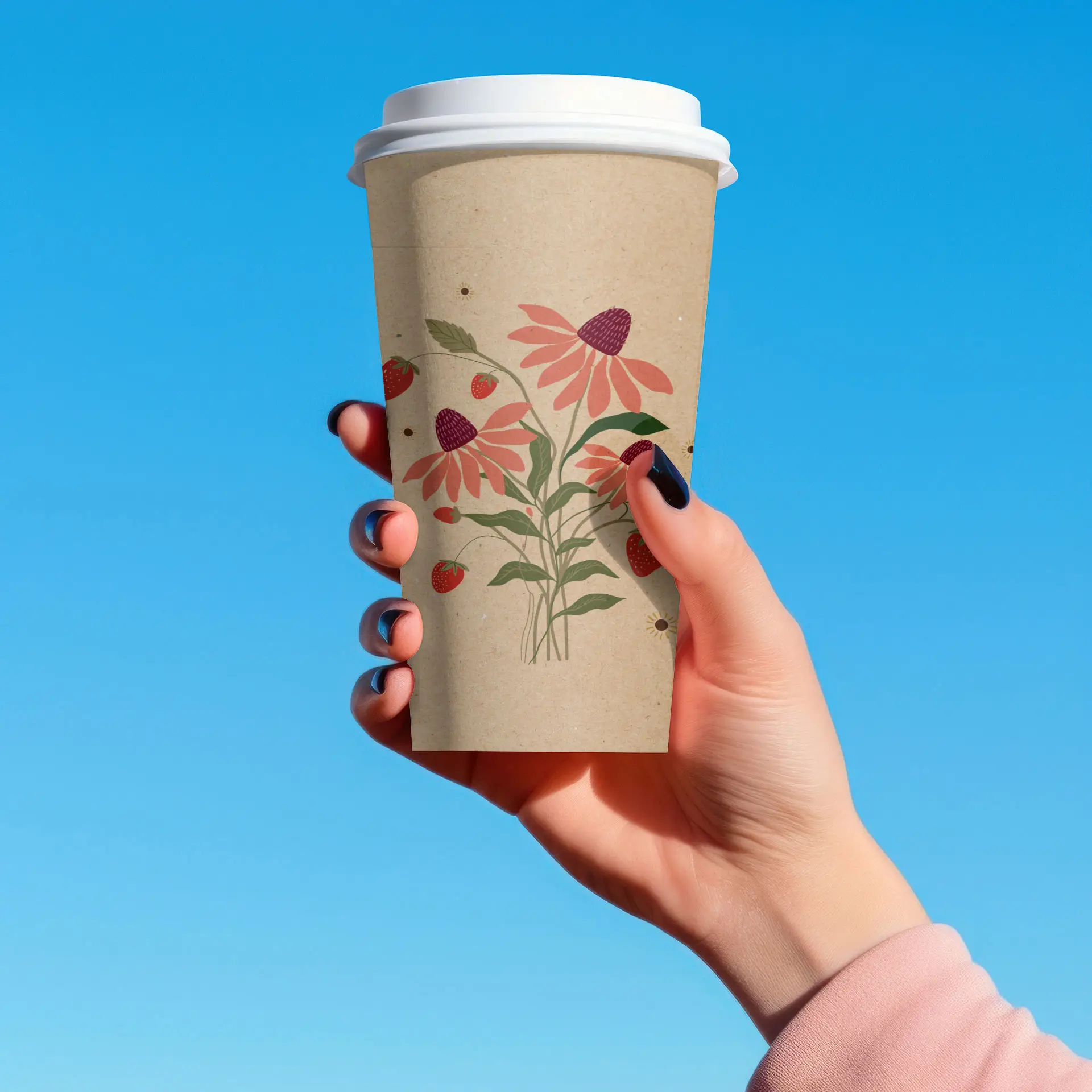 Brąski papierowy kubek z kwiatowymi wzorami w ręce na tle niebieskiego nieba.