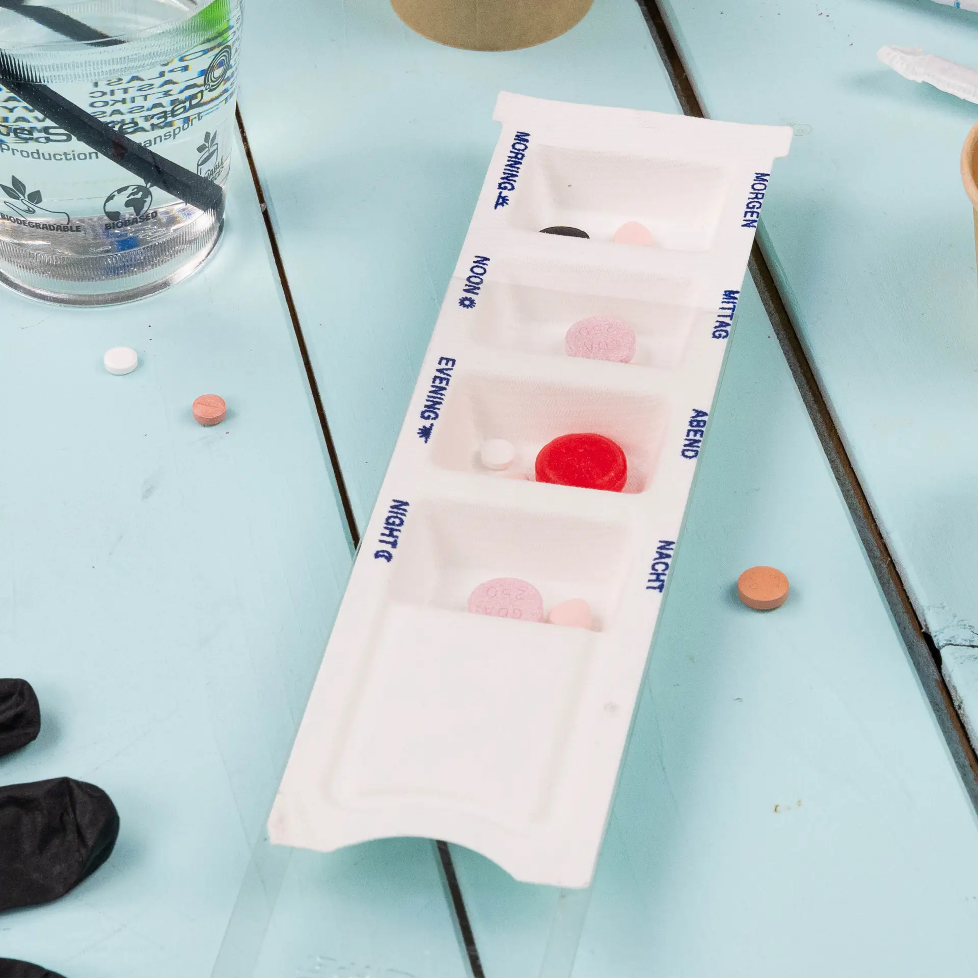 Biodegradowalny dozownik leków wykonany z bagassy z czterema przedziałami na ranek, południe, wieczór i noc; pokazana pokrywka z rPET.