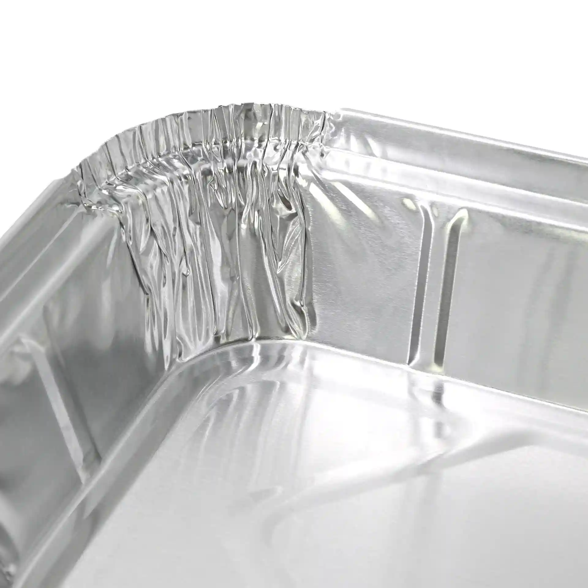 Zbliżenie rogu prostokątnego pojemnika aluminiowego, pokazujące zagięte krawędzie i błyszczącą powierzchnię.
