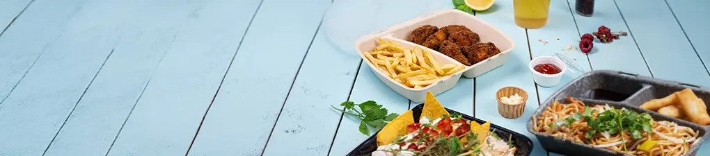 Zielony rysunkowy szef kuchni z łyżką obok pojemnika z jedzeniem; niebieskie drewniane tło.