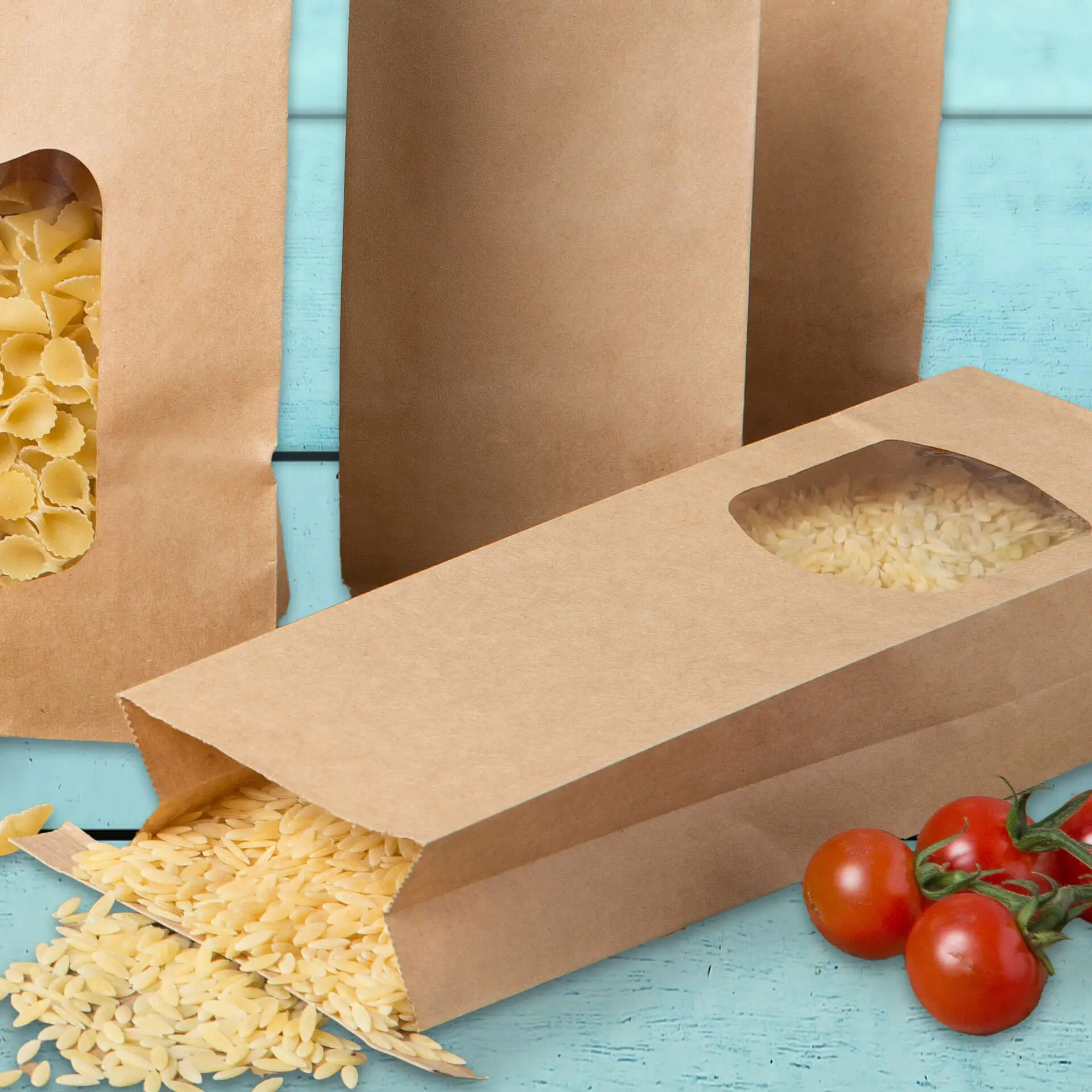 Brązowe papierowe torby z dnem prostokątnym i okienkami; jedna torba przewrócona z przedmiotami, otoczona świeżymi pomidorami na niebieskim tle.