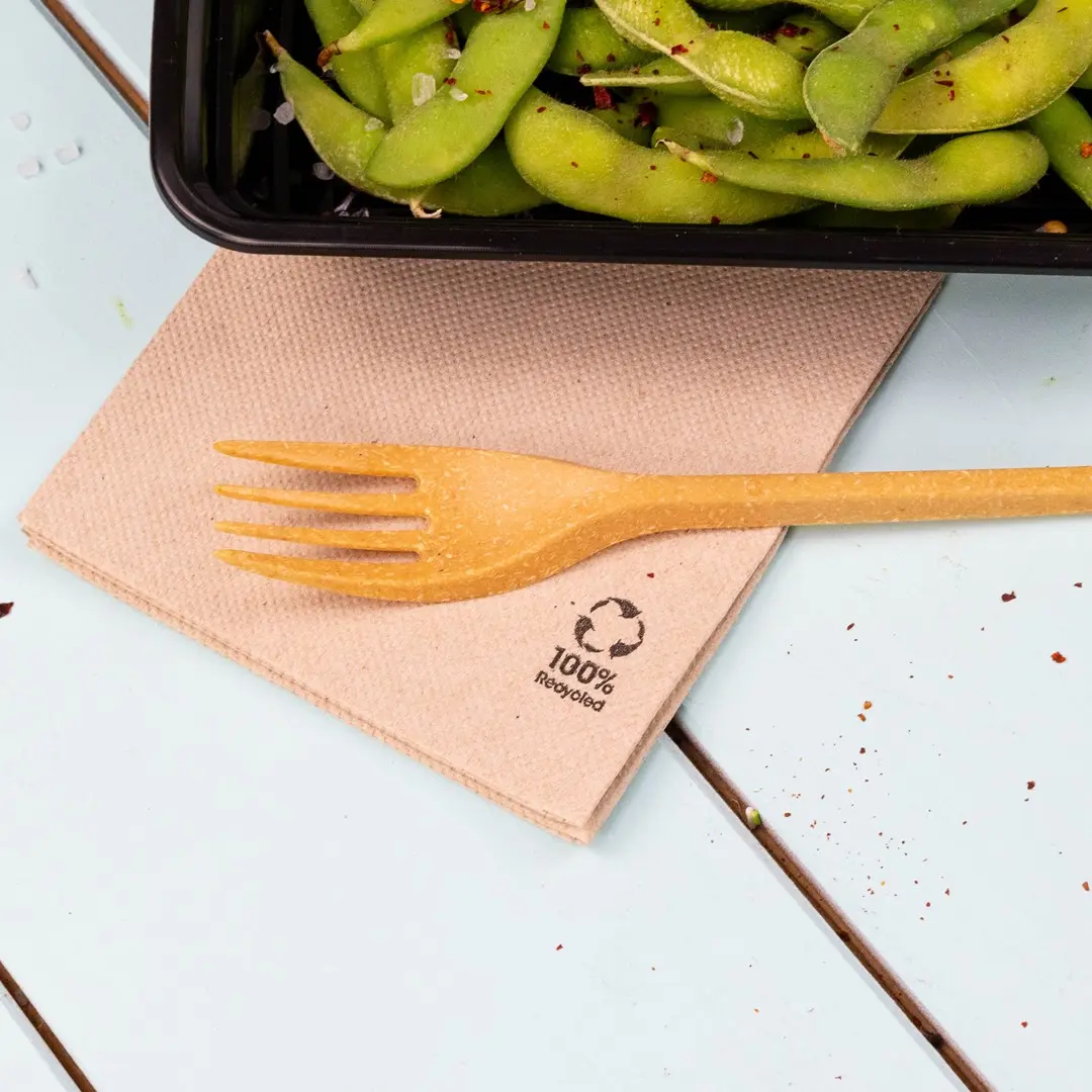 Brąserweta z żółtą widelcem na niej, obok czarnego pojemnika z edamame.