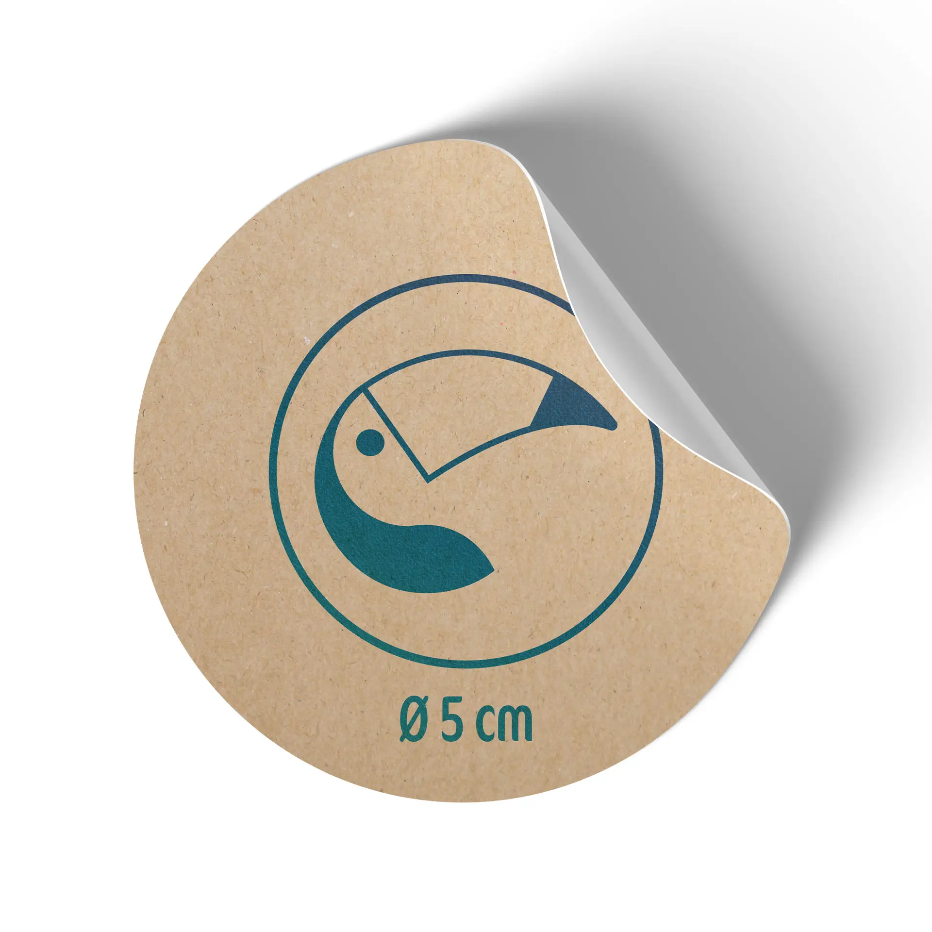 Okrągła etykieta z papieru kraft, 5 cm średnicy, z niebieskim wzorem tukana i lekko odklejonym tłem.