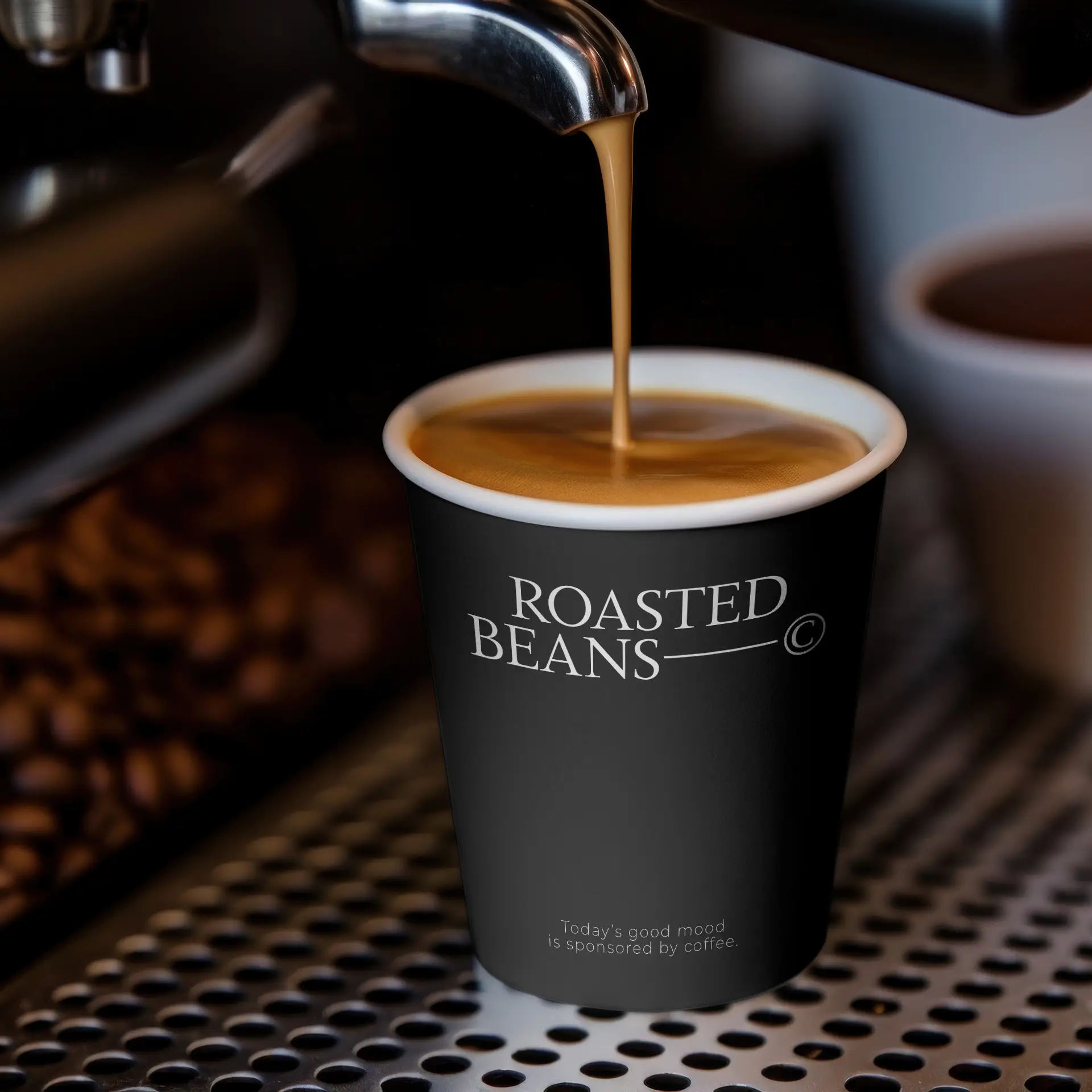 Kubek wypełniony kawą, z czarnym wzorem z napisem "ROASTED BEANS", stoi na metalowej powierzchni.