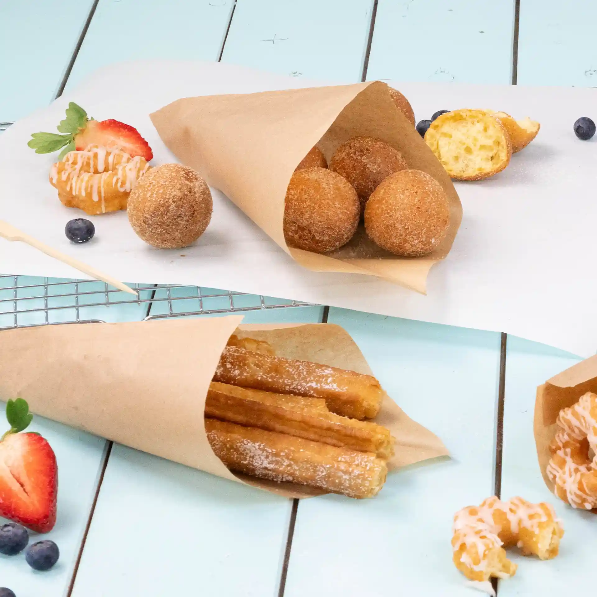 Obraz brązowych papierowych torebek z frytkami, w tym churros i kulkami pączkowymi, na jasnoniebieskiej powierzchni.