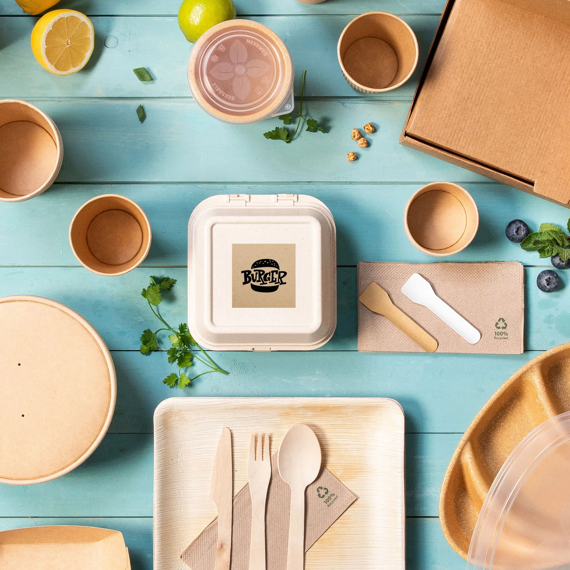 Kwadratowy pojemnik z papieru kraft z logo burgera, otoczony różnymi jednorazowymi opakowaniami żywności i sztućcami.