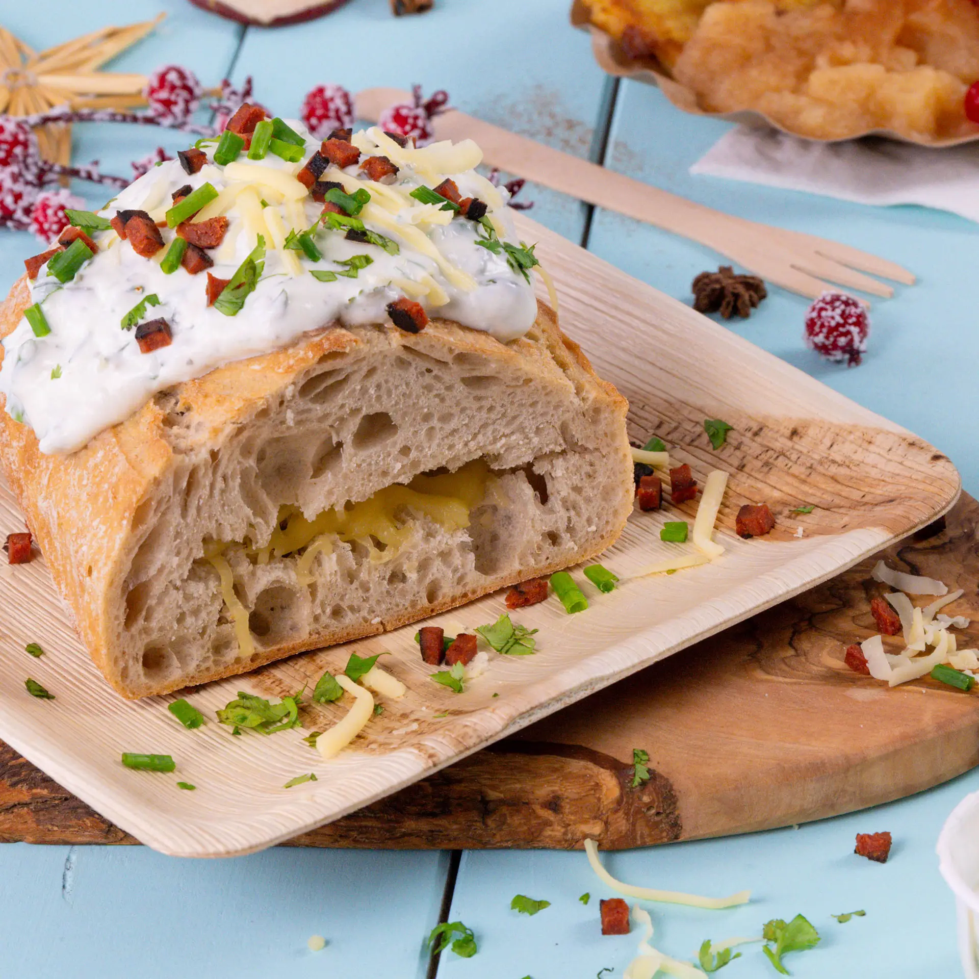 Kwadratowy talerz z liści palmowych z pokrojonym chlebem, posypanym sosem, serem i ziołami, ukazujący naturalny wzór słojów.