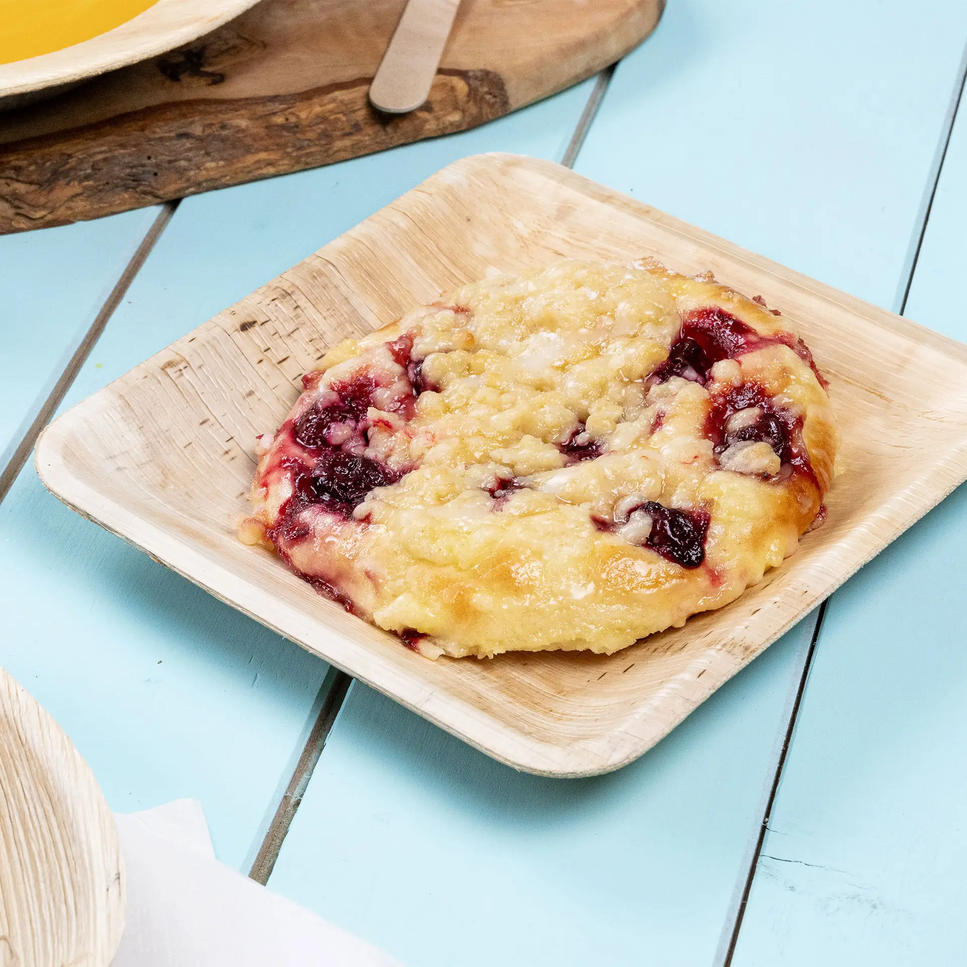 Kwadratowy talerz z liścia palmowego z pieczonym deserem z czerwoną owocową nadzieniem; talerz ma naturalny wzór słojów.