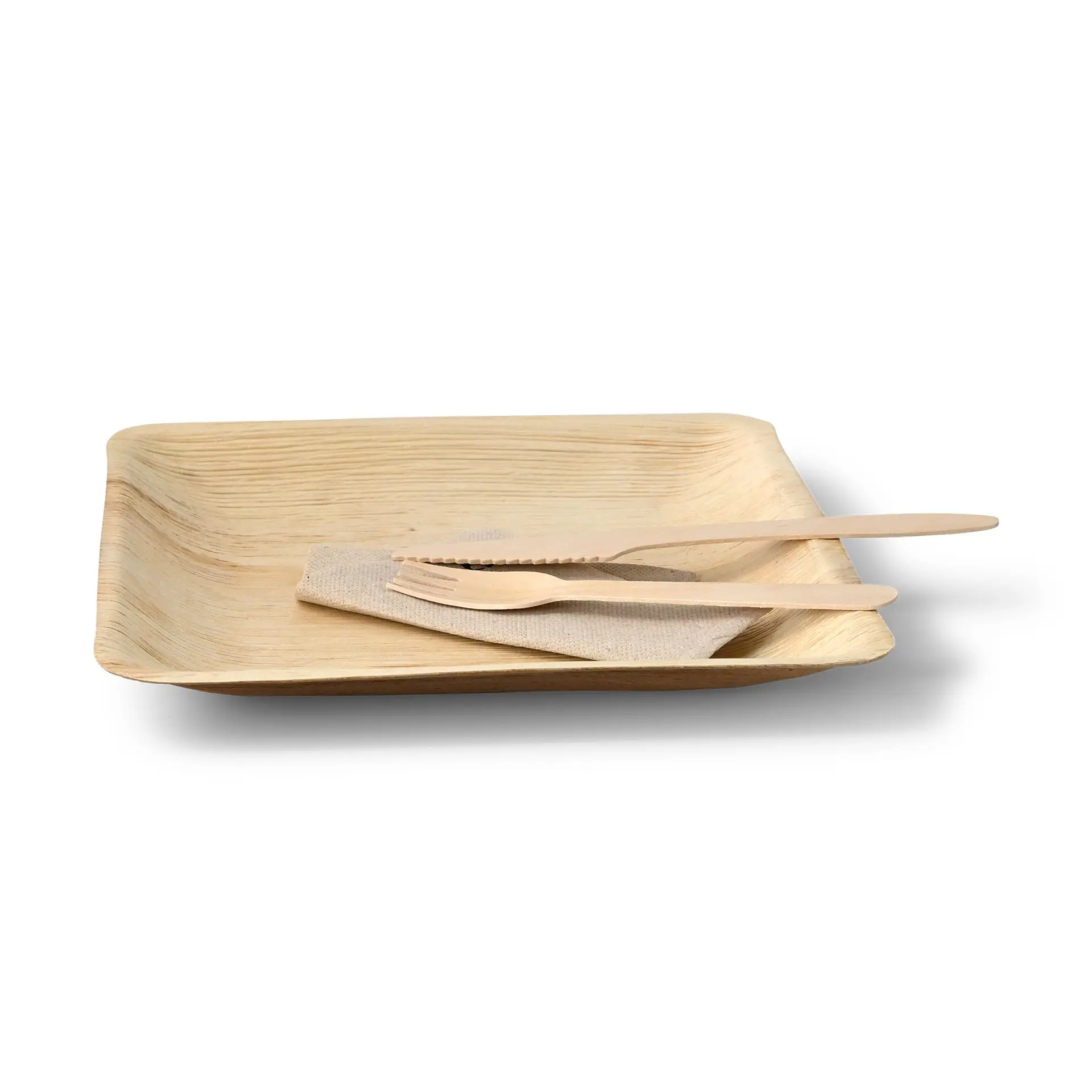 Kwadratowy talerz z liścia dłoni z małym brzegiem na sos, w towarzystwie drewnianych sztućców i materiałowej serwetki.