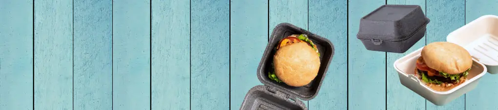 Zielony kucharz z kreskówki z łyżką, obok burgera w brązowym pudełku na wynos na niebieskim tle z drewna.