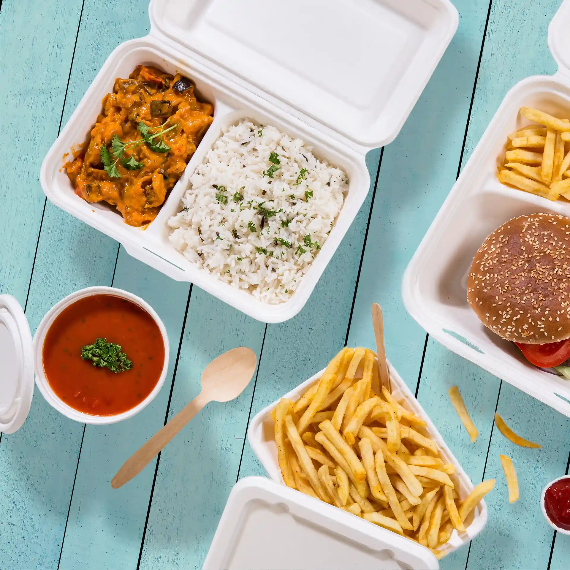 Obraz kremowo-białego pojemnika z trzciny cukrowej z dwoma przegródkami, zawierającego ryż, curry, frytki i burgera.