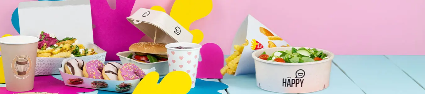 Układ fast food na wynos z burgerem, frytkami, kolorową misą sałaty, sosem i napojem na niebieskiej powierzchni.